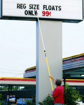 Person changing letters on an outdoor marquee sign with a letter pole